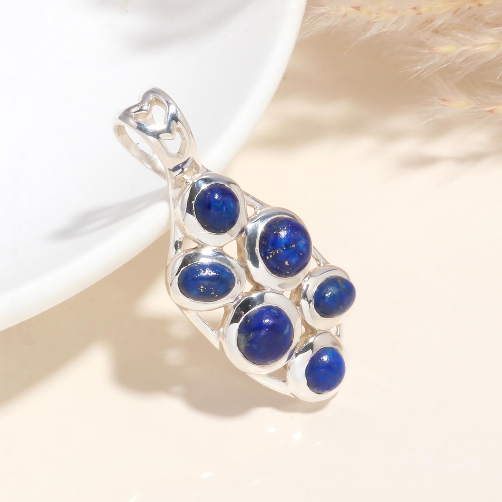 A sterling silver pendant with multiple round lapis lazuli gemstones, displayed against a light background.