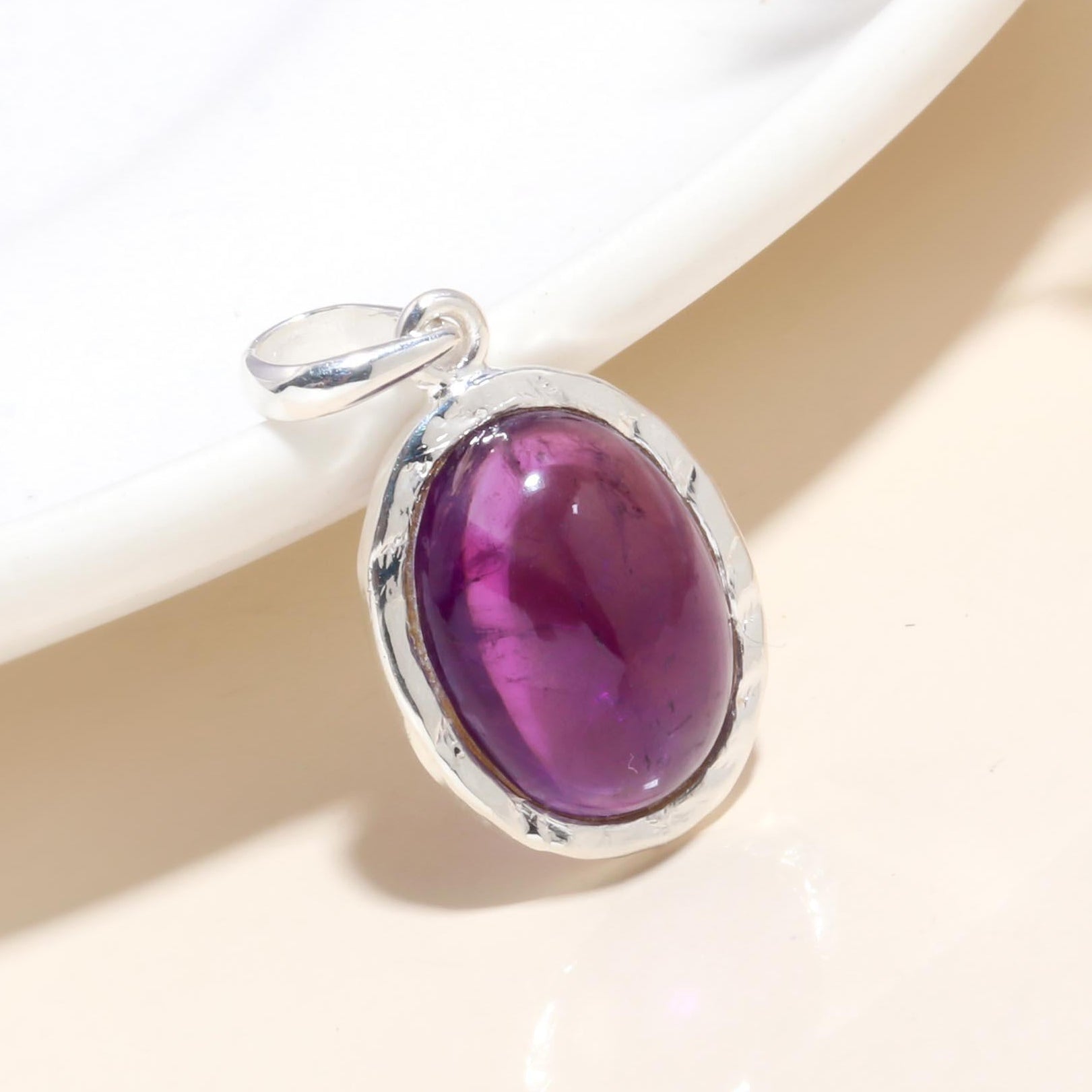 A 925 sterling silver oval pendant with a purple amethyst gemstone, displayed against a light background.