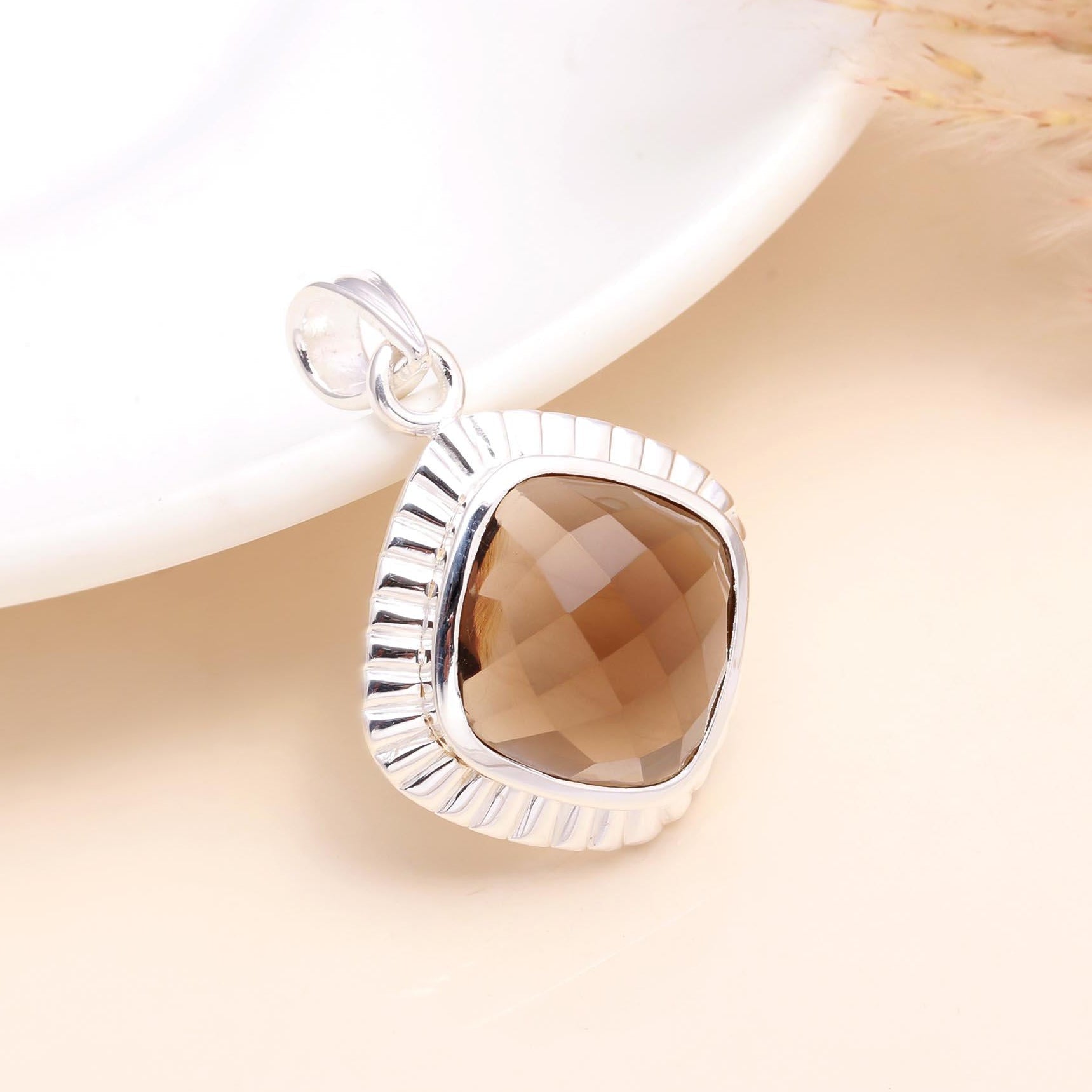 A 925 sterling silver cushion cut smoky quartz pendant placed on a white surface, with a Faceted cut gemstone.