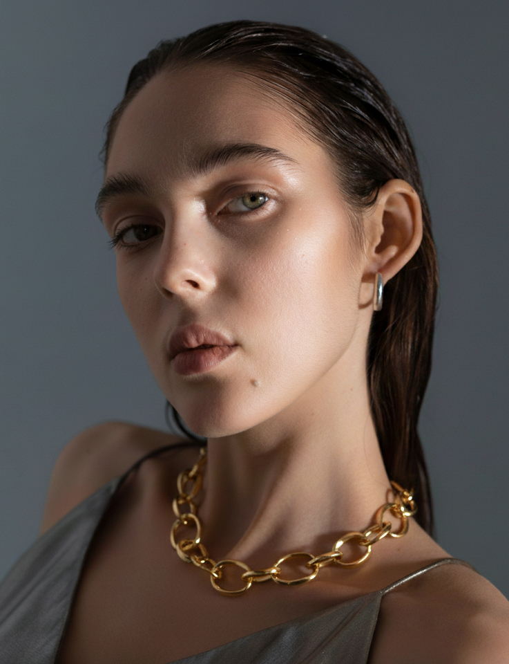 Woman wearing a gold chain necklace against a gray background