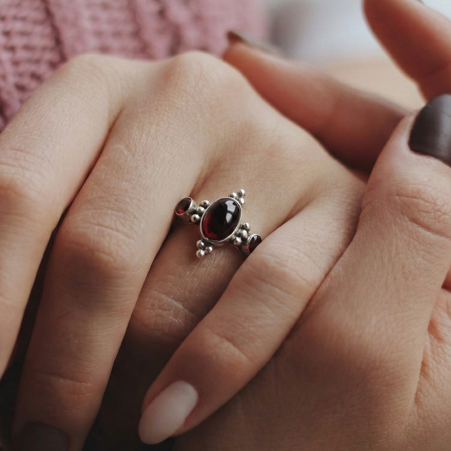 Close-up of a hand wearing a decorative ring with a red gemstone.