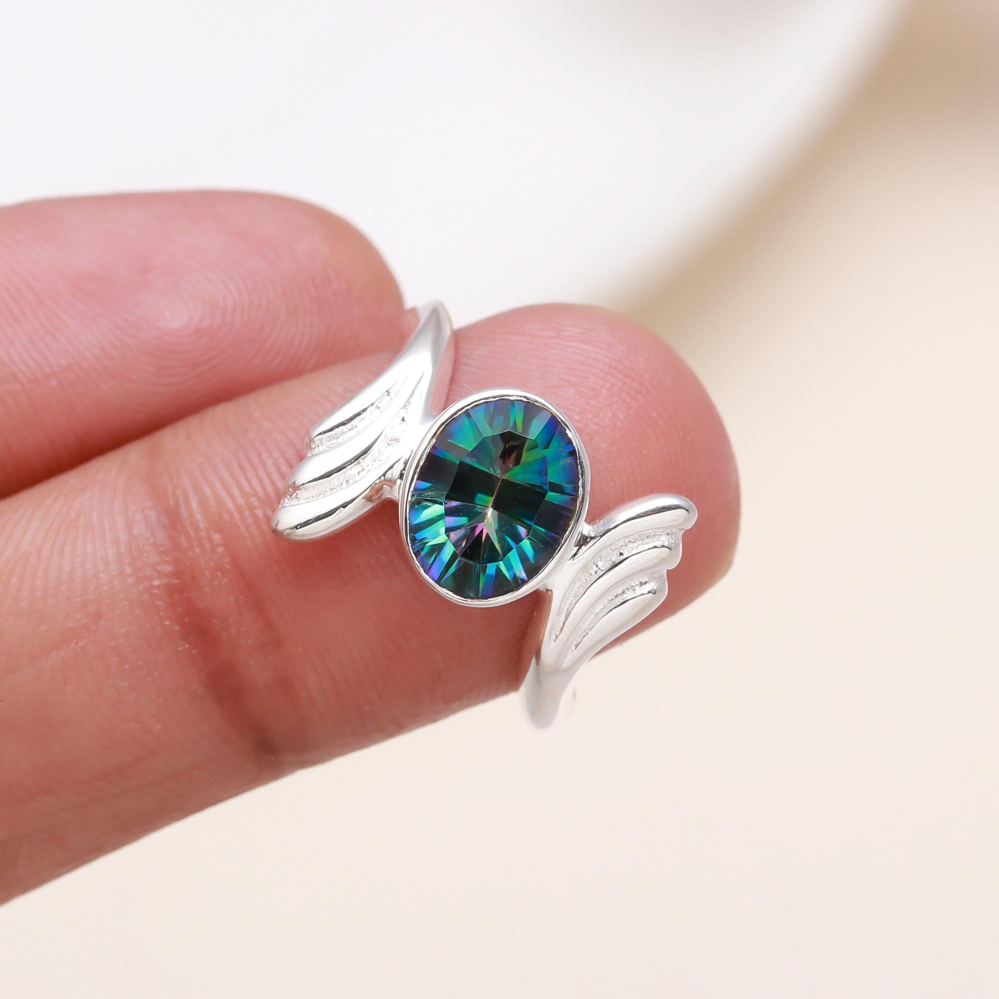 Elegant oval mystic topaz ring on finger with open wing design