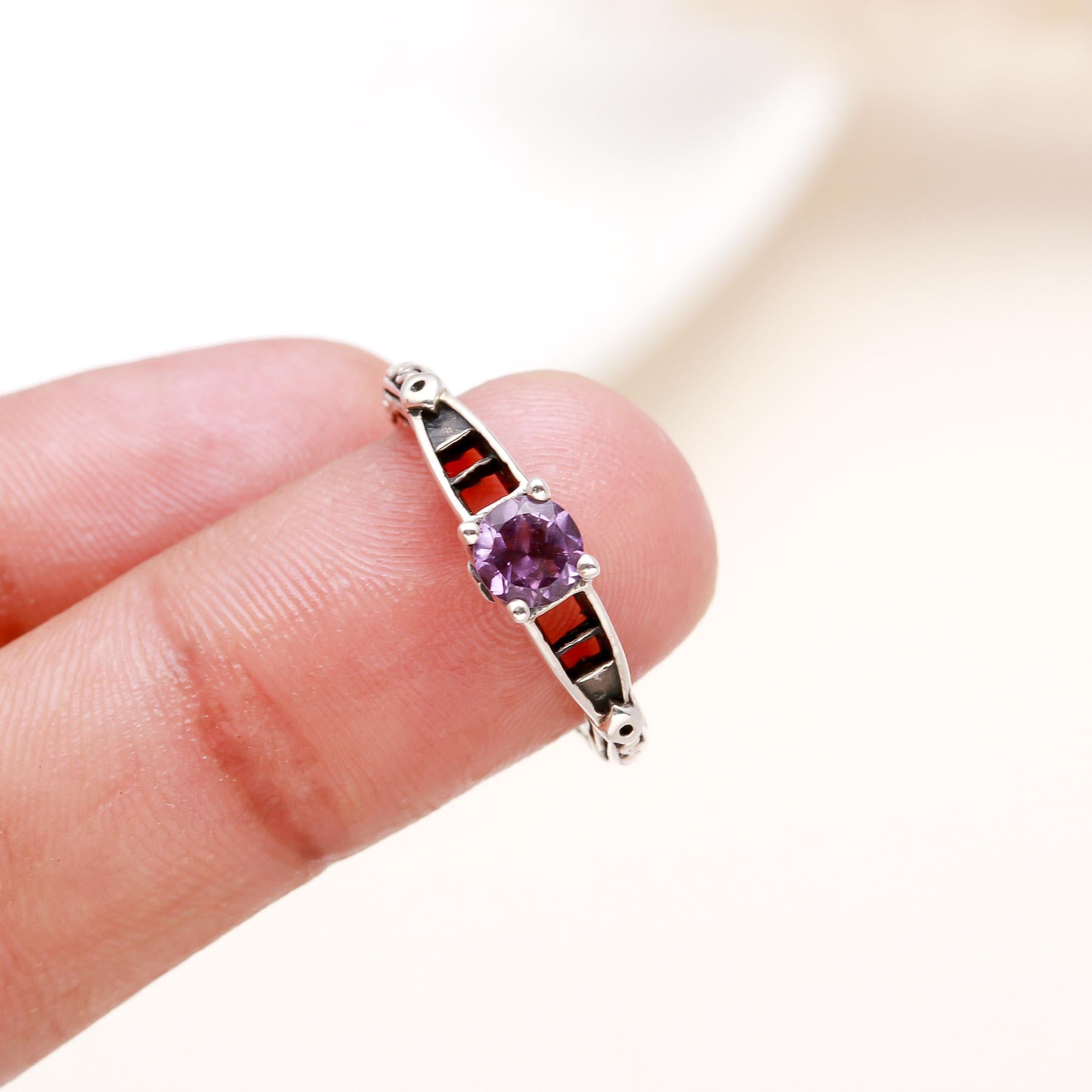 Elegant amethyst ring with red enamel accents on finger