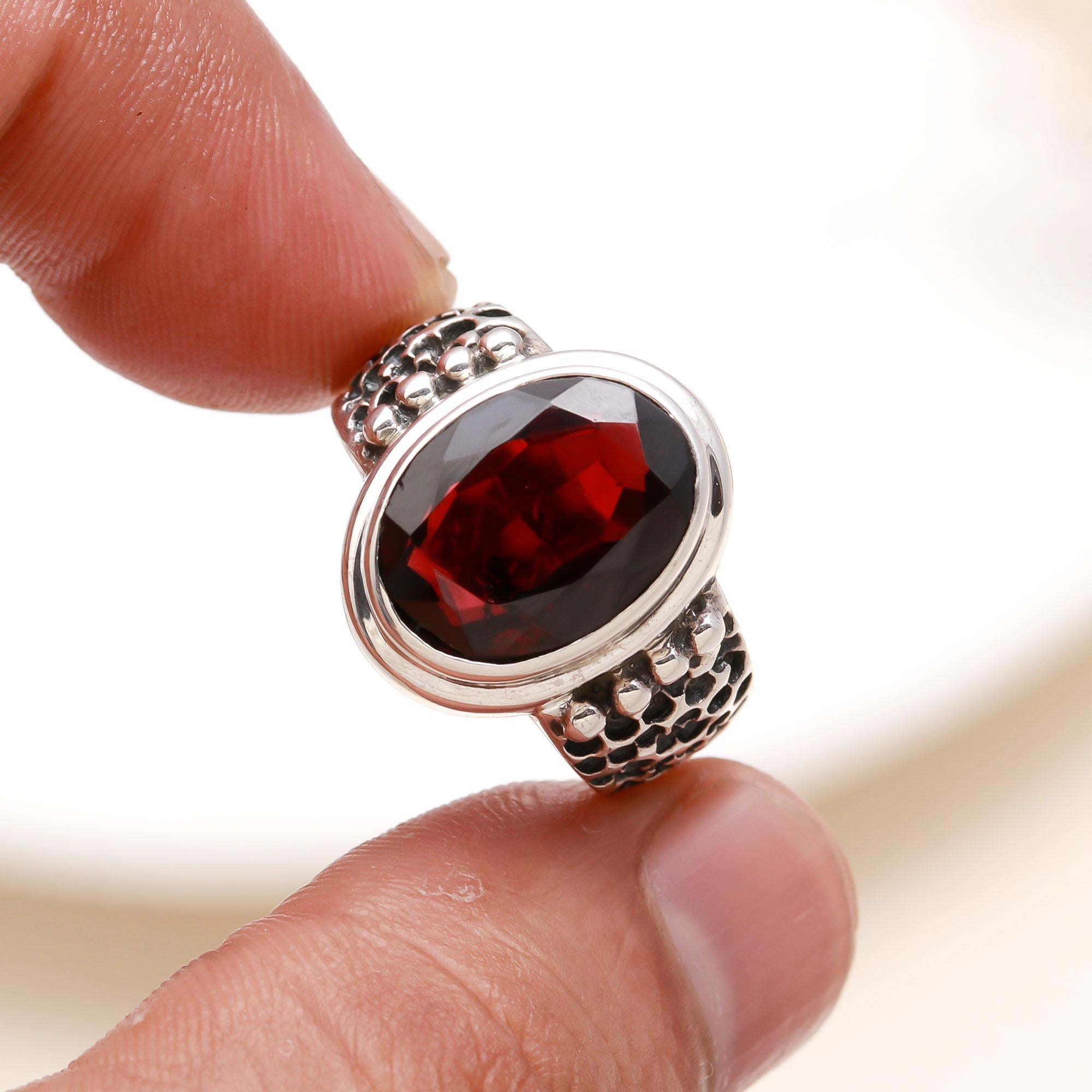 Elegant garnet gemstone ring with textured band on finger