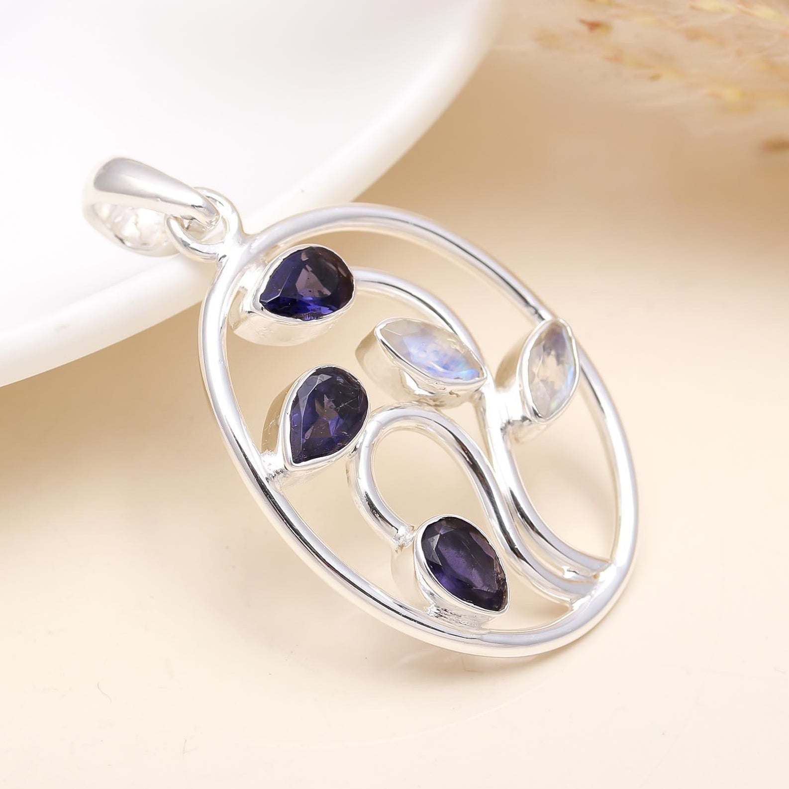 A silver pendant featuring a central faceted iolite gemstone with a polished finish, surrounded by a sleek, modern design.