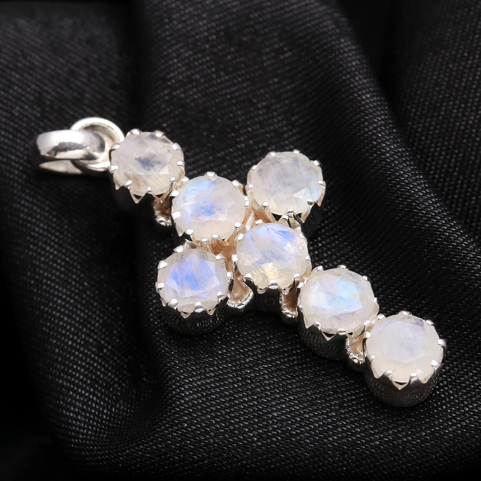 Silver pendant with rainbow moonstone stones on a black fabric background