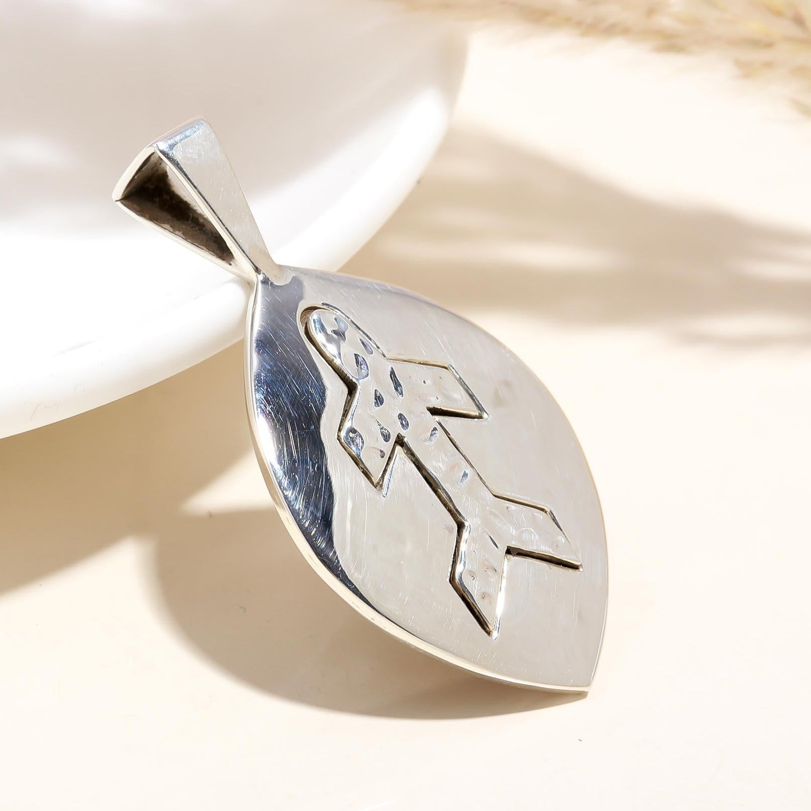 Silver pendant with an engraved design on a light background
