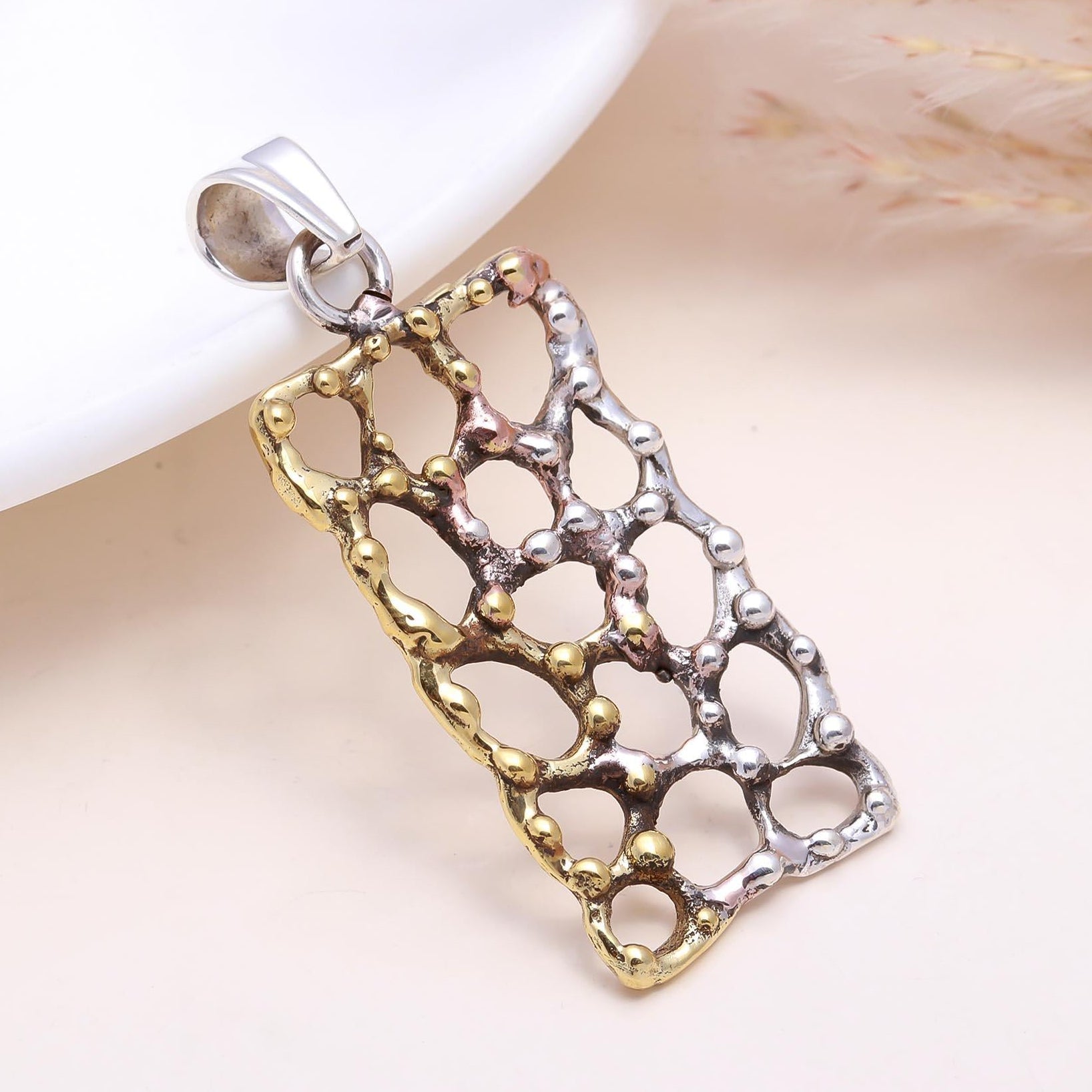 Two-tone silver and gold pendant on a white background