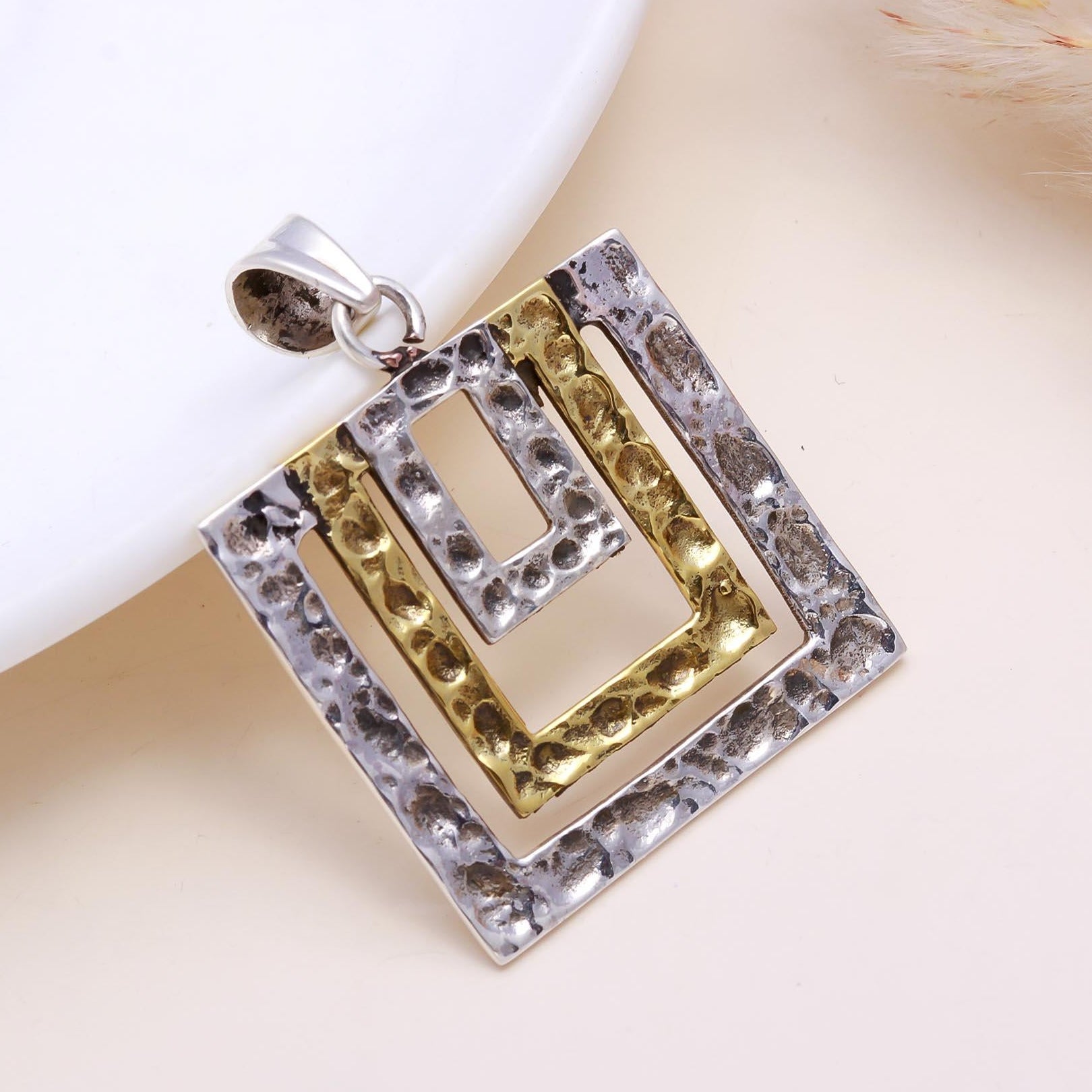 Gold and silver pendant on a light background