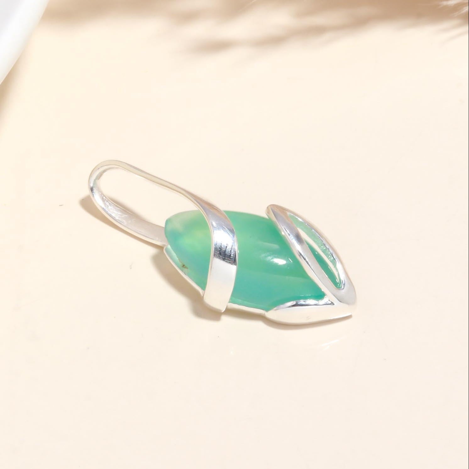 Green pendant with silver setting on a beige background