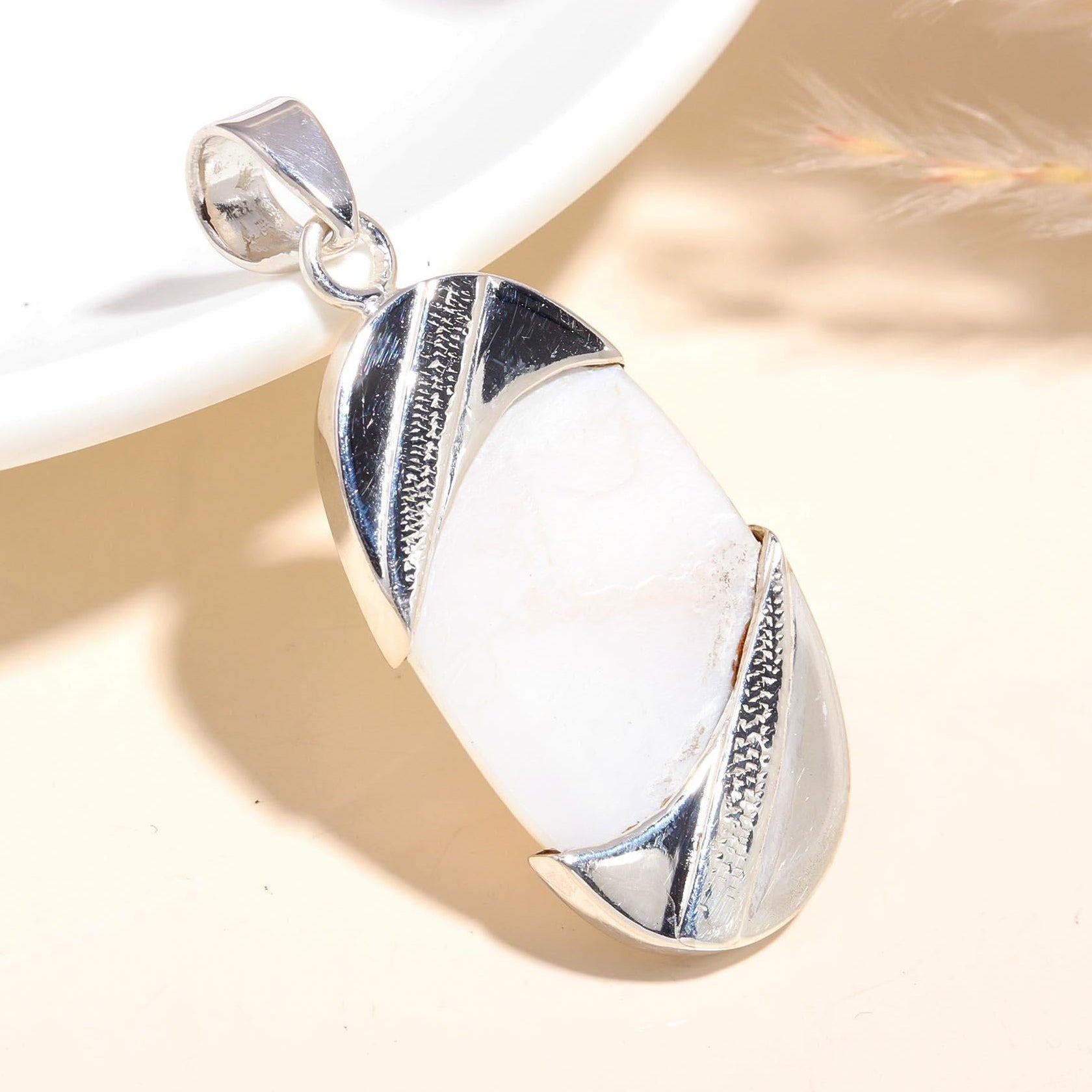 A sterling silver Art Deco pendant with a white gemstone, displayed against a neutral background.