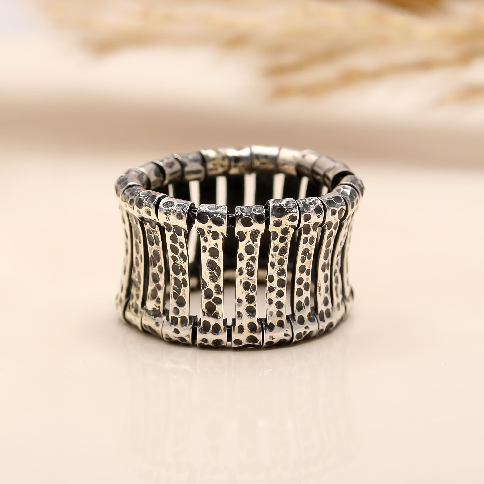 Silver ring with textured design on a beige background