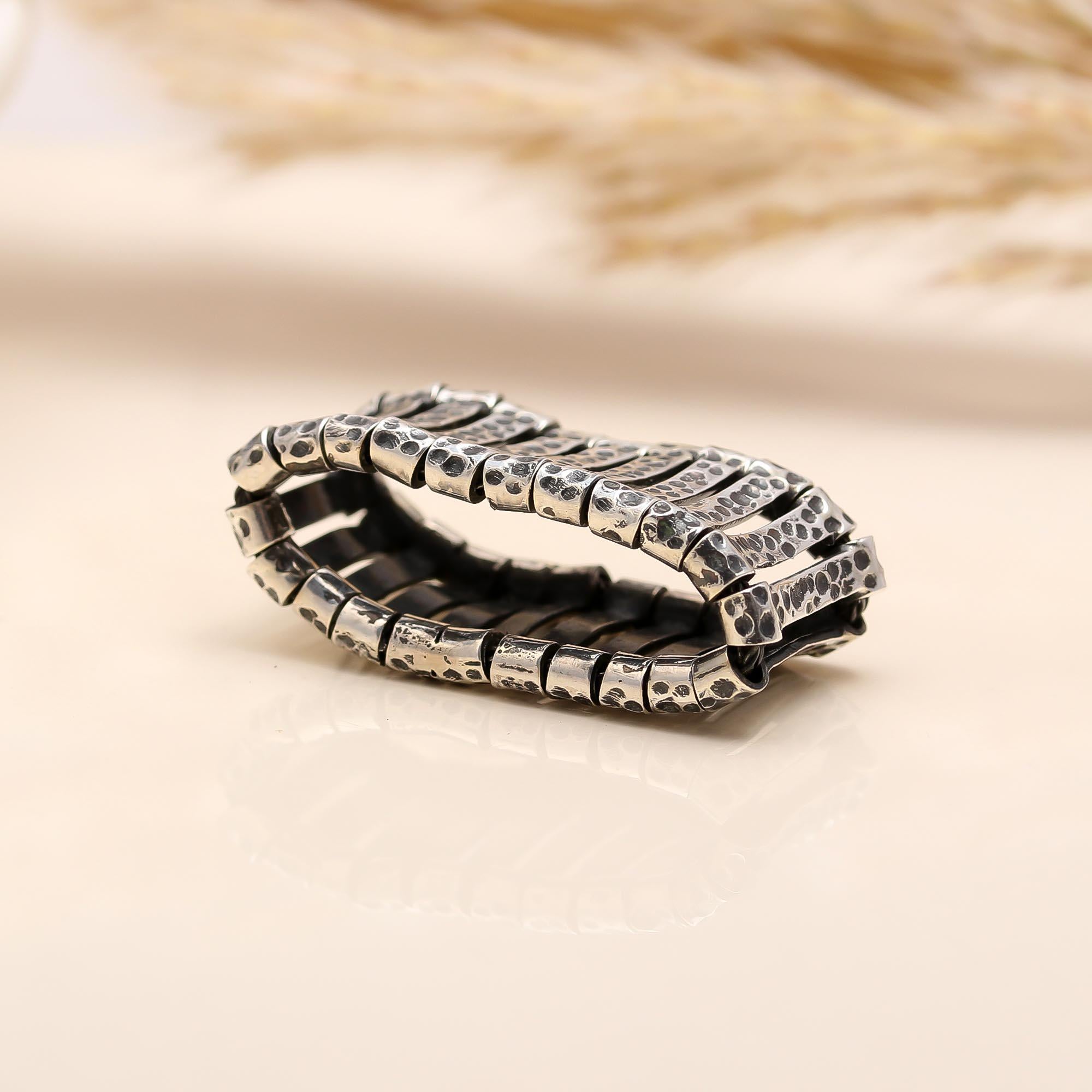 Silver ring with textured design on a beige background