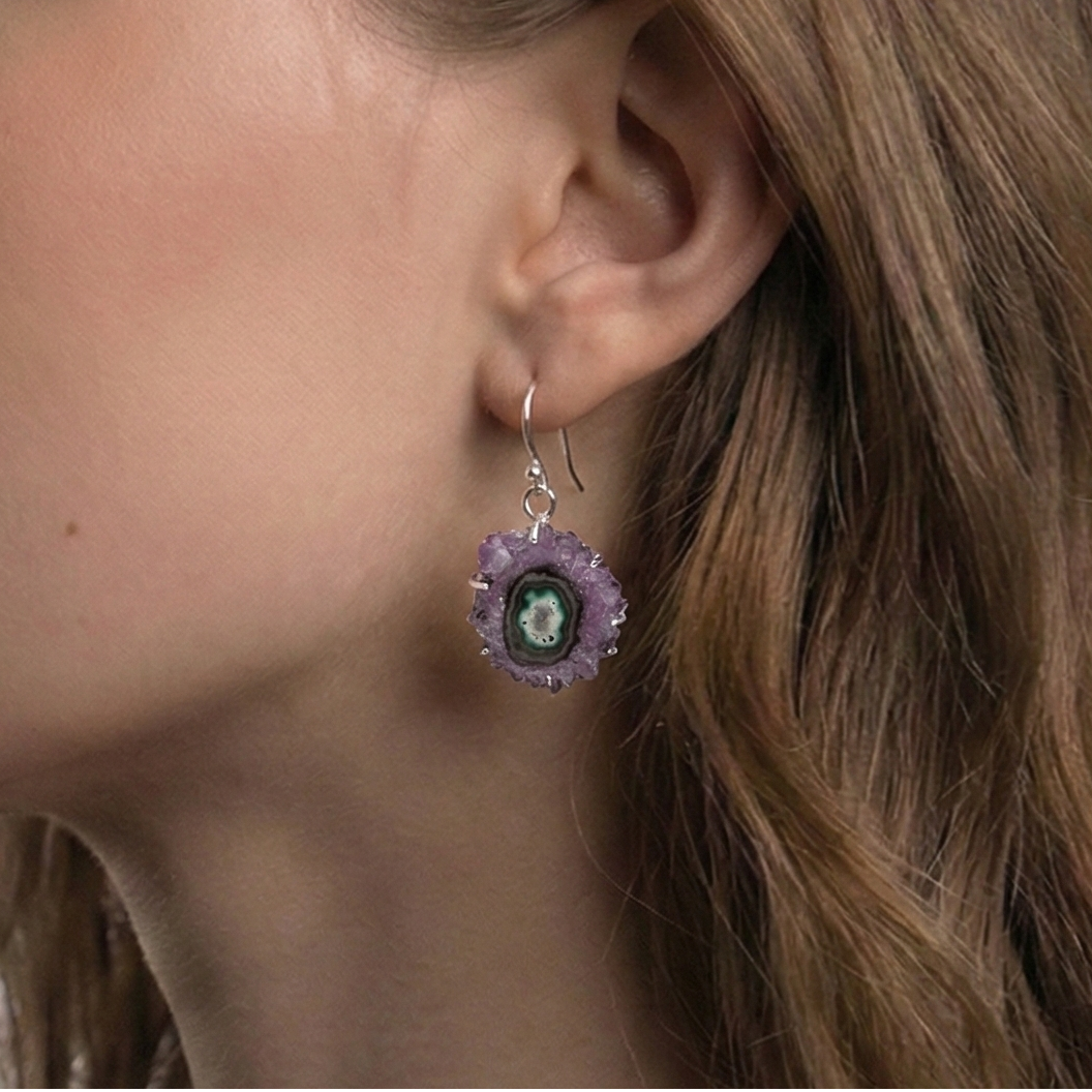 Close-up of a woman wearing a floral earring with a green gemstone on a white background