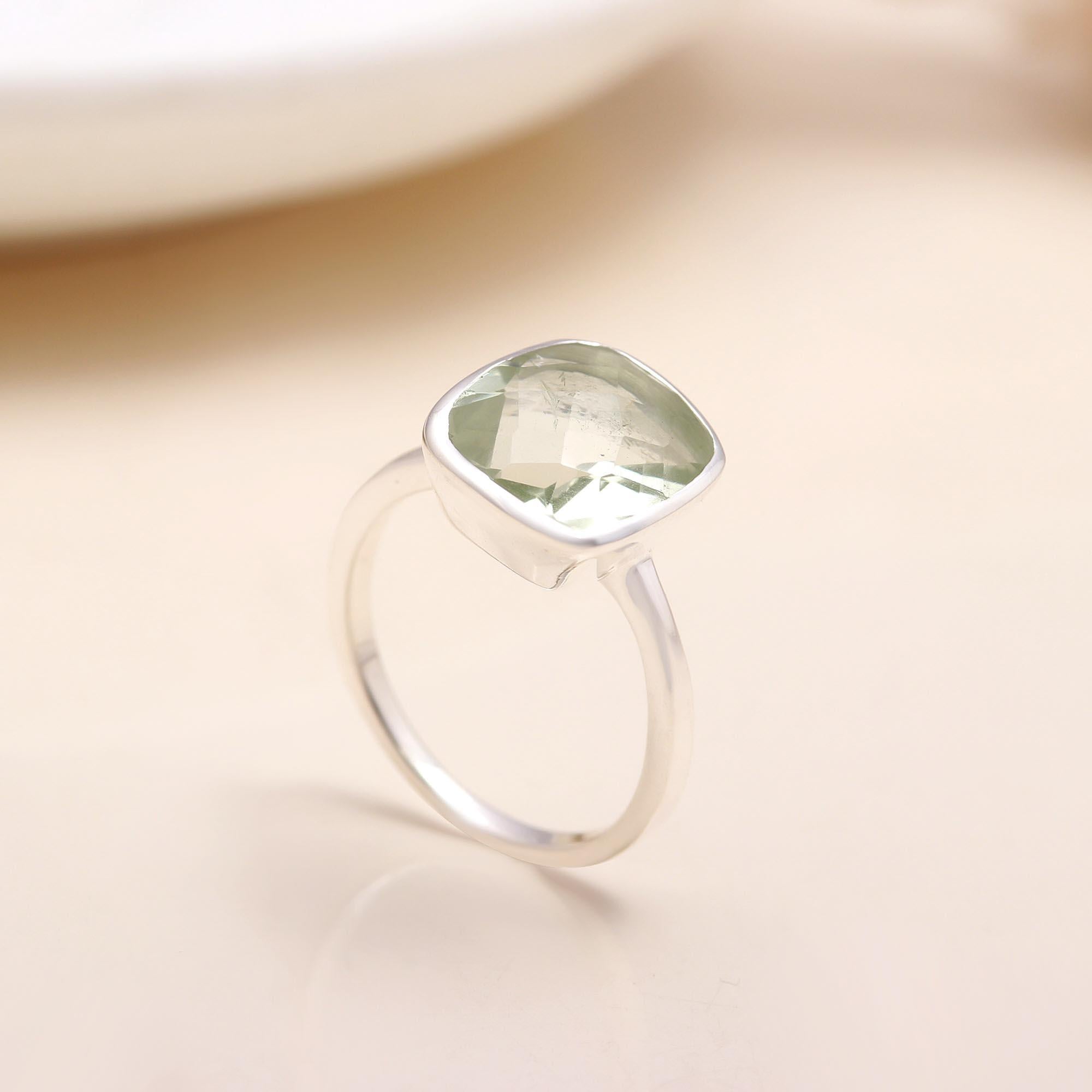 Silver ring with a green gemstone on a beige background
