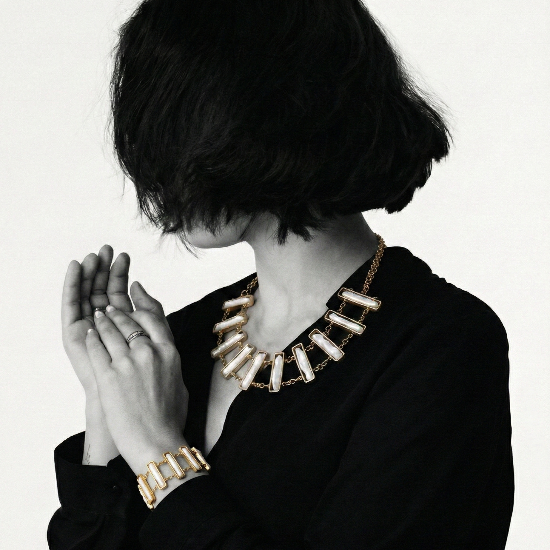 Person wearing a gold necklace and bracelet on a white background