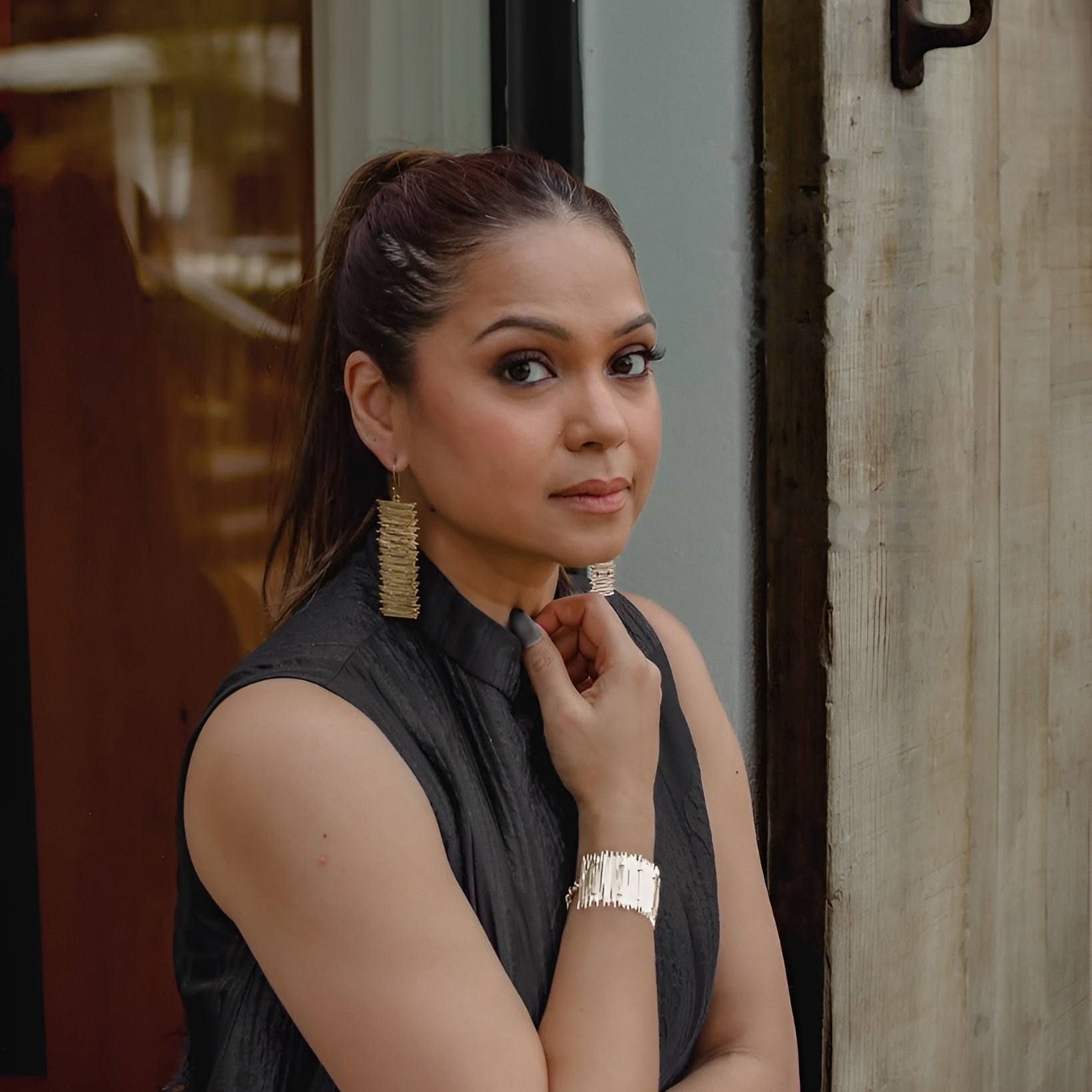 Woman wearing a gold statement bracelet and earrings